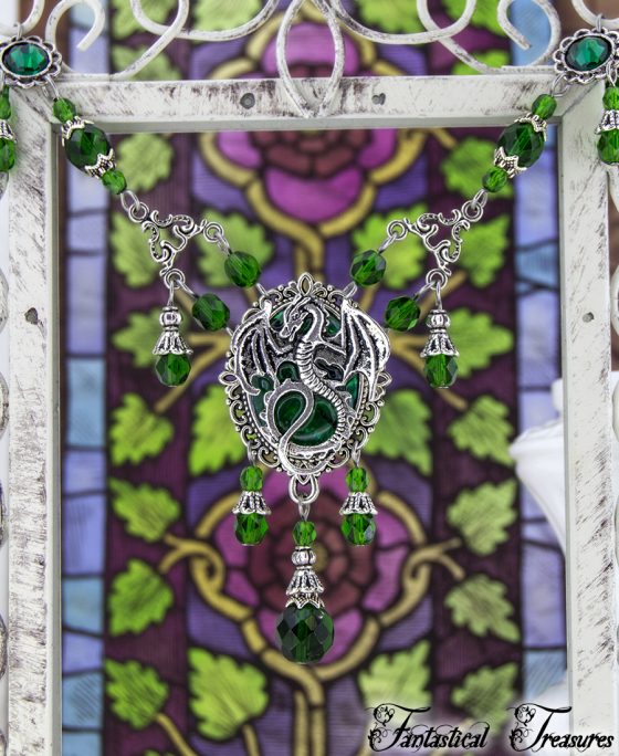 Green Cameo dragon necklace hanging on frame close up against a fancy background