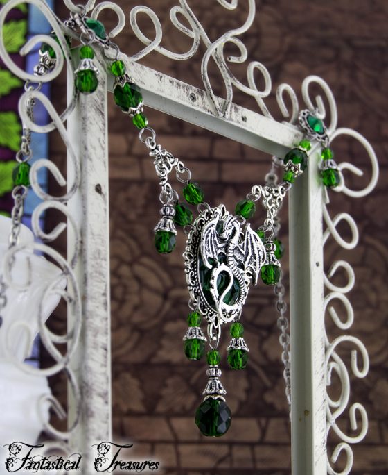 Green Cameo dragon necklace hanging on frame taken against a fancy background